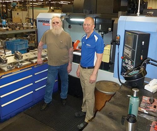 Here you can see how the placement of the tool cabinet, the pallet loading/unloading station and the machine tool itself allow Mr. Simpson (with Ryan Hart, process engineer, at right) to reach all areas of activity in his workstation with minimum twisting motion. 