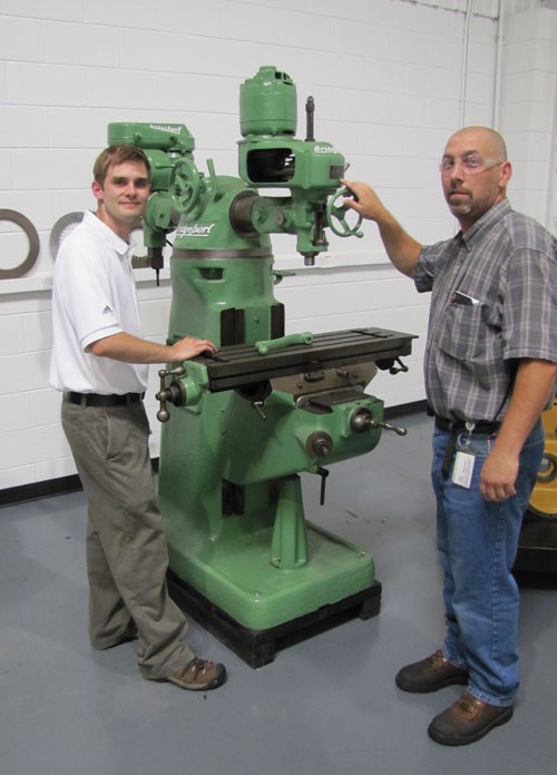 Joel Neidig (izquierda) y el gerente de la planta Argos, John Deitl, al lado de la primera máquina-herramienta de ITAMCO, la cual sigue en operación.