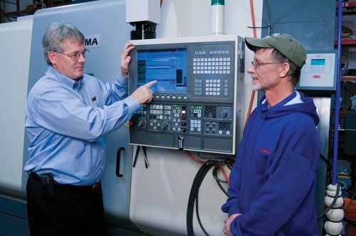 Randy Lewis of LNS America demonstrates the e-Connect system to Robert Silcott, lead machinist at Nilpeter.