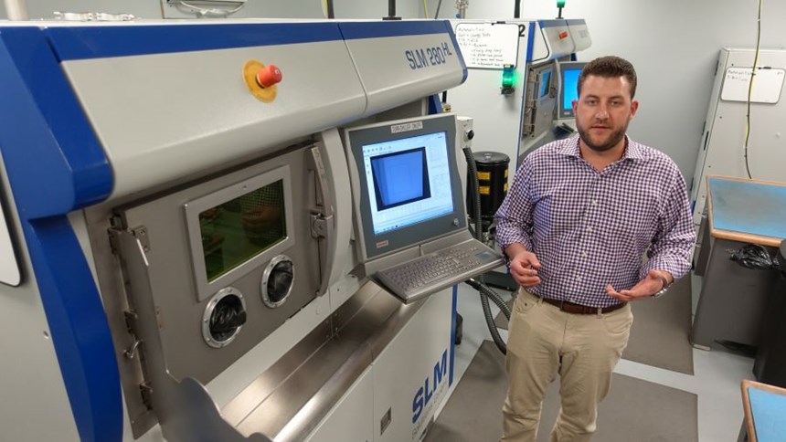 Christian Joest in front of the SLM Solutions machines used for 3d printing in a machine shop