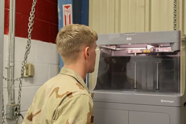 A photo of a soldier looking into one of Markforged's printers