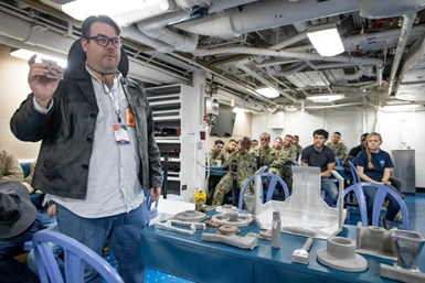 Spee3D Co-Founder and CTO Steve Camilleri shows the company’s metal 3D printed parts to the U.S. Navy. Photo Credit: U.S. Navy photo by Eric Parsons