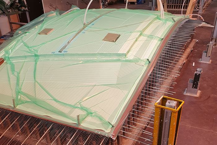 Curved composite sandwich panel production on an adaptive mold