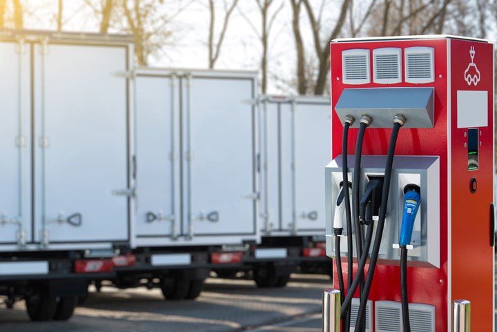 Electric vehicles charging station on a background of a row of trucks.