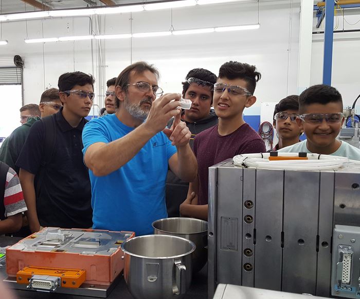 Graham Ballard, lead mold maker at M.R. Mold and Engineering, show visiting students a liquid silicone rubber (LSR) part 