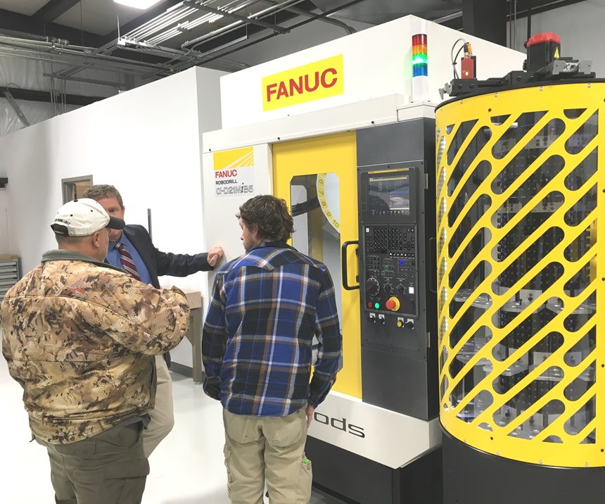 Attendees gather around a Fanuc Robodrill fitted with a robotic arm for transferring parts from the integrated storage unit to the worktable.