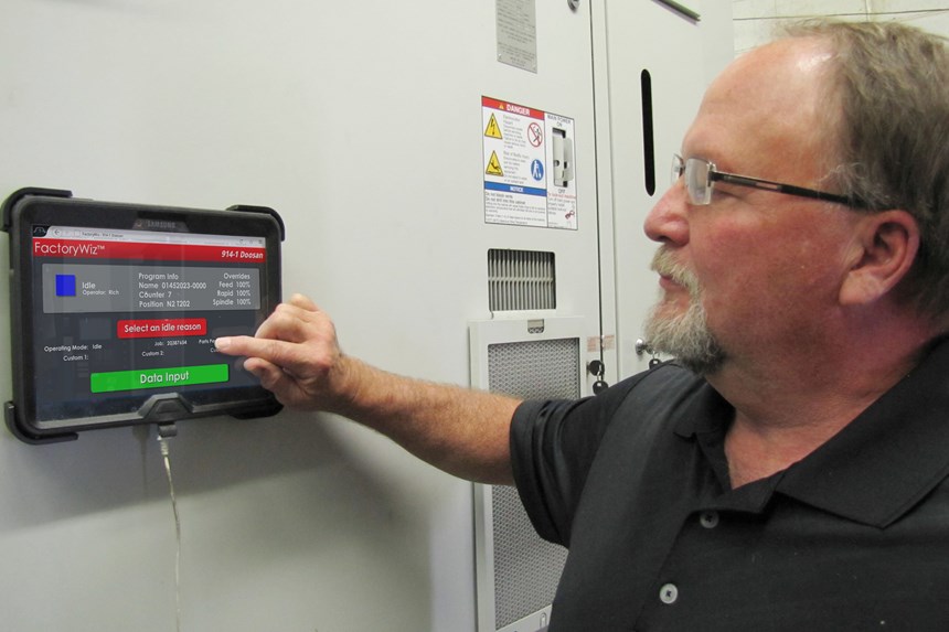 Terry Worthan, quien lideró la instalación del sistema de monitoreo de máquina FactoryWiz, señala una tablet de operador montada en una estación de trabajo de máquina.