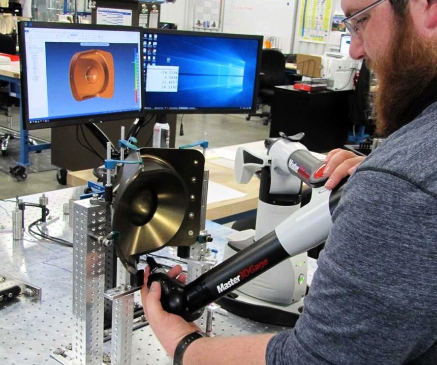 Jake Blankenbeker inspecciona un componente aeroespacial en una fijación que fue creada usando una versión impresa en 3D para esta parte.