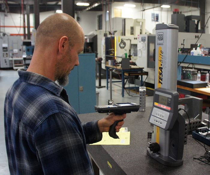 Machinist Dan Aldrich uses a handheld unit to scan the barcode on a height gage before use.  