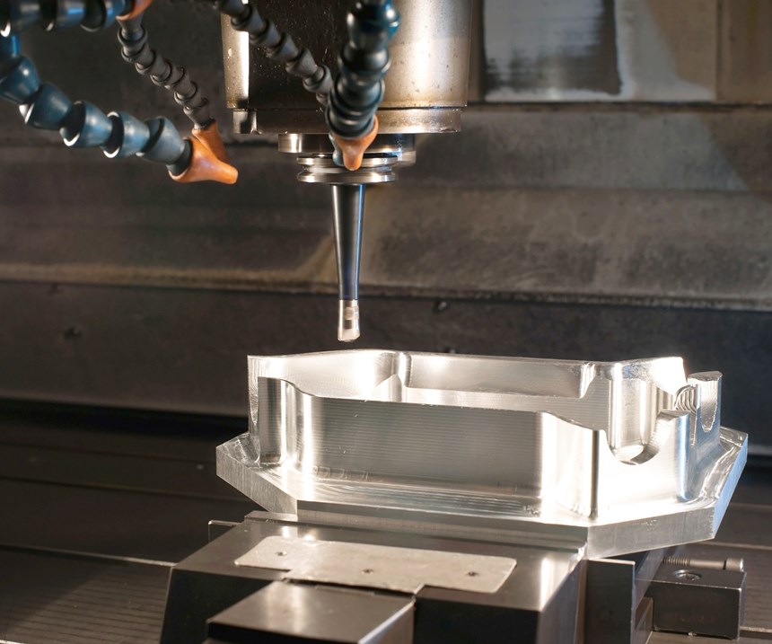 A three-axis end mill approaches a mold cavity for a machining operation within the workzone of a three-axis vertical machining center. 