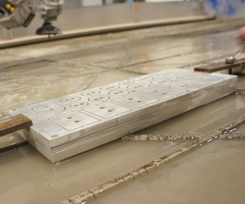 Mounting a stack of shims to the waterjet table between two aluminum plates enables cutting all the geometry at once. 