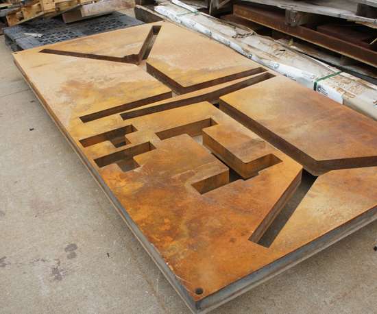 The waterjet has already machined a large manifold from this piece of steel, the top and bottom portions of which were Blanchard-ground for flatness beforehand. The extra material will sit behind the shop until an opportunity arises to cut other parts from the same plate. 
