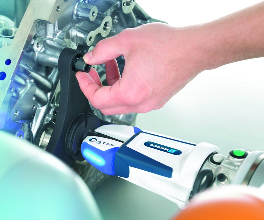 A cobot with a Schunk Co-act gripper holds a part in place while a person assembles it