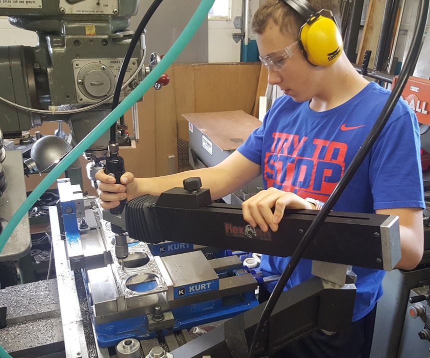 Shop owner Rob Little’s 13-year-old son taps holes on a component with the FlexArm