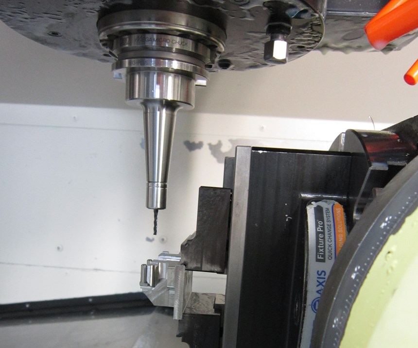 A long toolholder with a cutting tool and a part on a rotary table inside a machine
