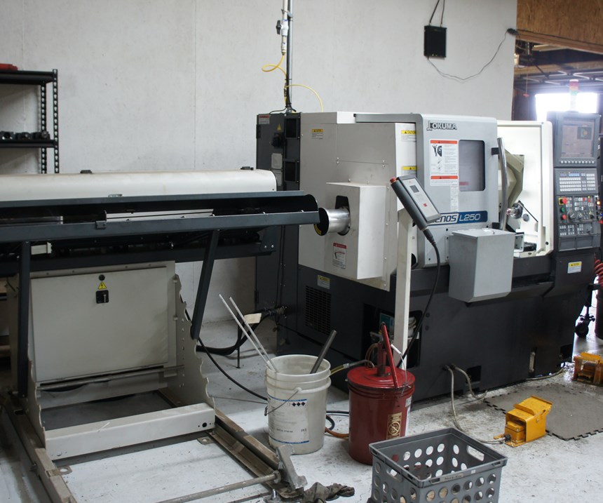 An Okuma Genos L250 lathe is equipped with a barfeeder for unattended operation.  