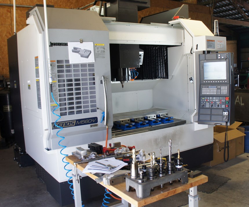 Wenteq's Okuma three-axis vertical machining center with the door open, set up and ready to machine. 
