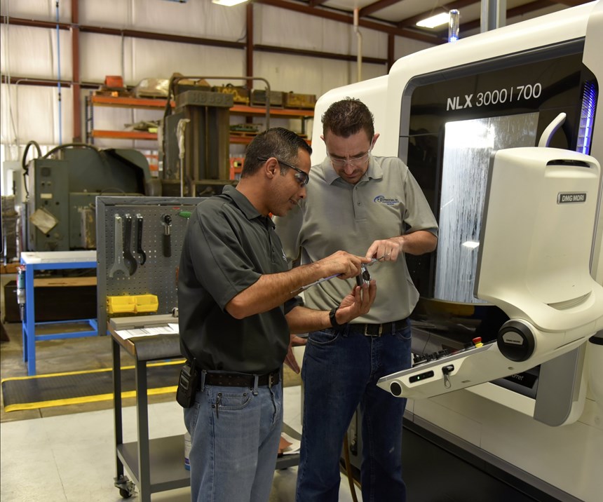 El gerente de operaciones, Mohsen Saleh, (a la izquierda) y el operario de máquinas CNC, Mark Garland, (a la derecha) discuten sobre una pieza de trabajo producida en uno de los centros de torneado universales DMG MORI NLX 3000 | 1250 de Anthony Machine.