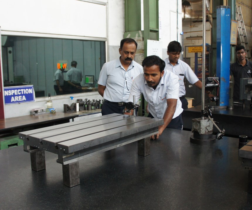 Employees measure a component at a BFW machine tool manufacturing facility. 