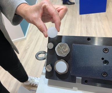 A photo of a person holding a chemical adhesive disc next to a workpiece.