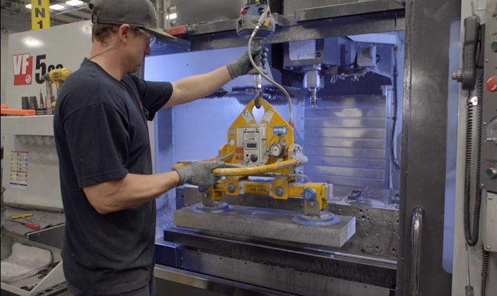 An operator loads a part into the fixture of a machining center at Cox Machine, an aerospace machine shop in Wichita, Kansas. 