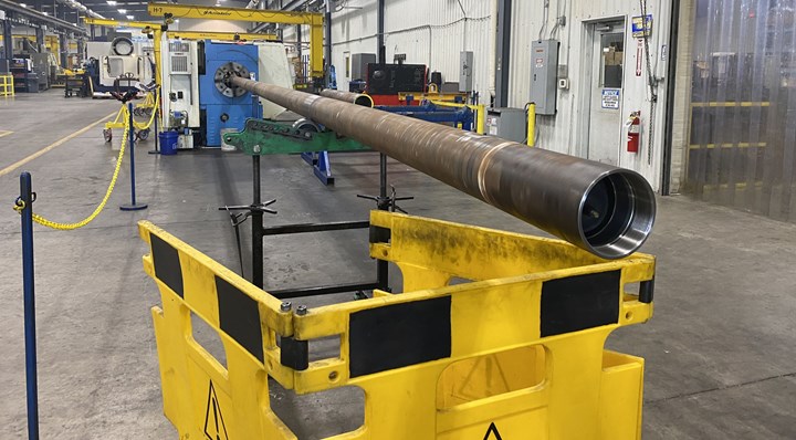 A large tubular component protrudes from the back of a lathe during processing at oilfield manufacturer Superior Completion Services. 
