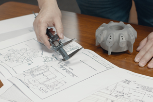 worker checking measurements between a CAD drawing and a 3D-printed part
