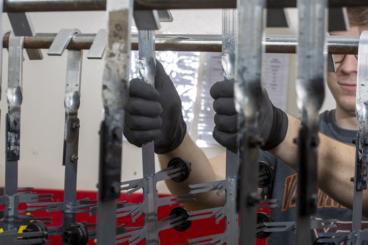 technician makes final adjustments to parts arranged on racks for finishing