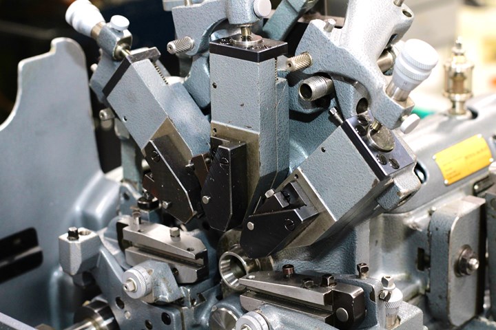 Cinco herramientas de corte rodean la pieza de trabajo en esta máquina tipo suizo de tornillo accionada por levas.