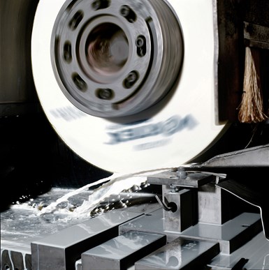 An image of a grinding wheel mid-operation, with coolant splashing beneath it.