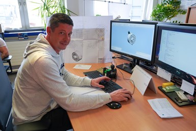 A photo of a smiling man working at a keyboard. EXAPT PLUS is open on two computer screens in front of him.