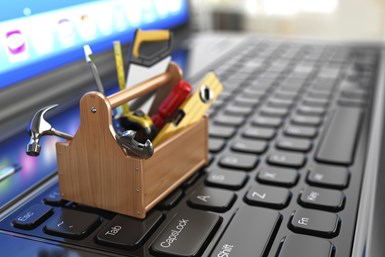 A stock photo of a miniature toolbox on top of a keyboard, with a computer monitor in the background