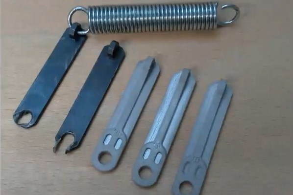 A photo showing the original spring holder hangers with damage from tearout alongside the redesigned AM versions.