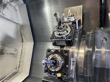 Various cutting tools are splashed with droplets of coolant in a close-up of a 12-station, live-tool turret in a CNC lathe. 