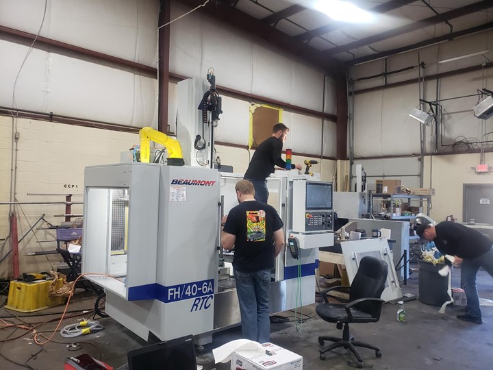 A fast-hole EDM drilling system’s enclosure is open for access as multiple team members at Beaumont Machine work to finish the assembly.  