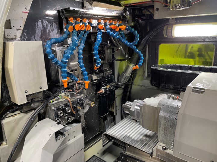 A view of the workzone of a Swiss-type machining center reveals various coolant hoses, tools and slides. 
