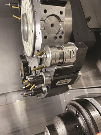 A measuring probe stands out amid the cutting tools in a close-up of a tool turret on a Swiss-type lathe. 