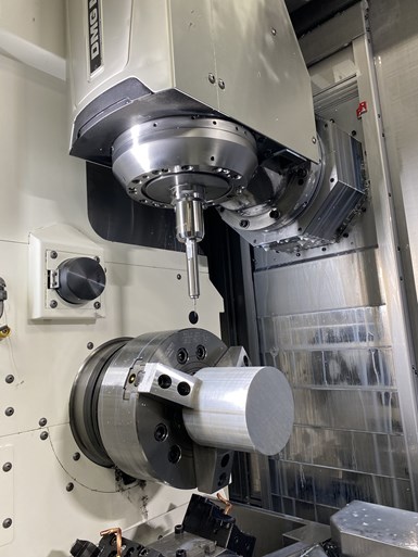 A milling spindle approaches a workpiece mounted in the chuck of a CNC machine tool. 