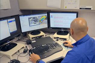 worker at desk with computer, looking at part designs
