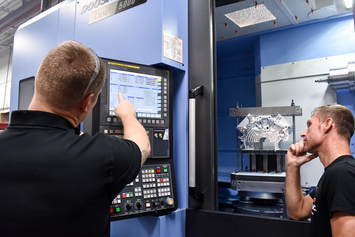 Two people working on a CNC control 