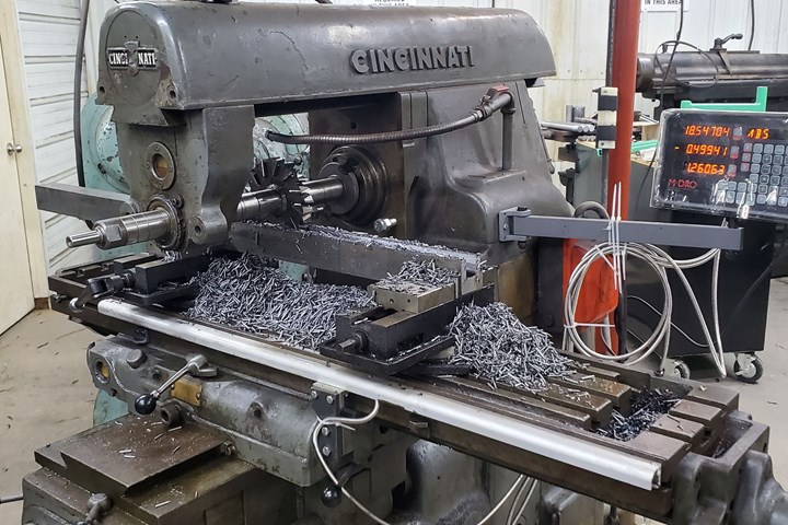 A large, rectangular toolholder in the foreground helps clear the cross slide on the manually operated turning machine visible in the background.