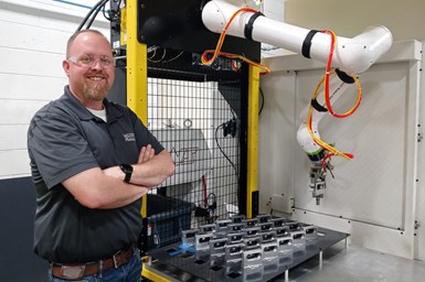 A photo of Kurt Wagner standing in front of a cobot frame.