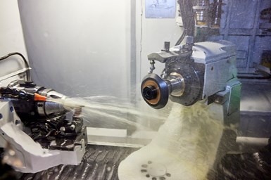 A photo of a grinding workzone, with coolant being sprayed at the wheel