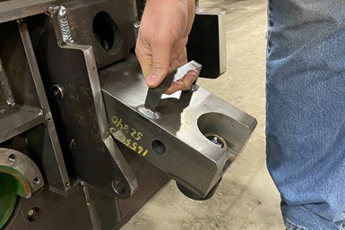 A photo of a man pulling the handle of a metal hook puller attached to a track rail.