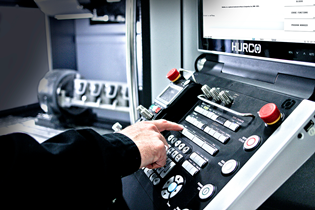 a Hurco machine control panel with a hand in frame from an operator, adjusting the machine