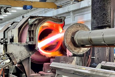 A CNC-controlled wheel approaching a red-hot metal tube within a furnace