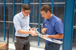 two workers looking at a metal aerospace frame part