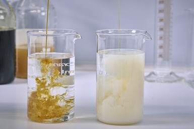 Image of two lab beakers, one with clear liquid and dark yellow substance being poured in and the other filled with a cloudy white substance