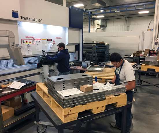 Fredy Nevas (right) helps form laser-cut parts on the company's press brake.