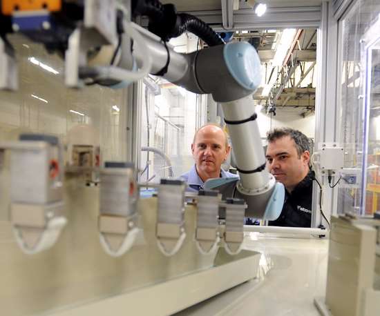 men looking at robot coating parts